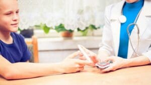 dijabetes, dječak radi kontorlu šećera kod doktora.