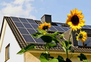 SolarAsolarni paneli energija cells on a roof with sun flowers in the foreground